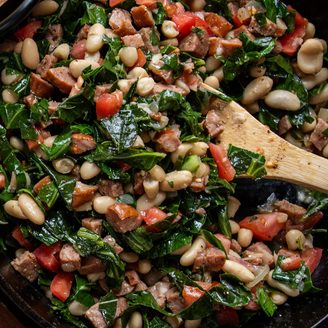 greens, white beans, tomatoes and north country smokehouse andouille style sausage in a skillet