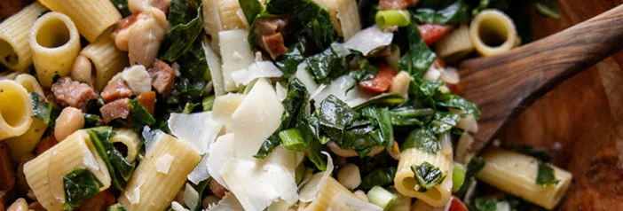 andouille sausage, pasta, beans and greens in bowl